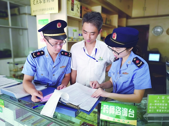 執(zhí)法人員在一家藥店檢查特殊藥品進(jìn)貨臺(tái)賬。