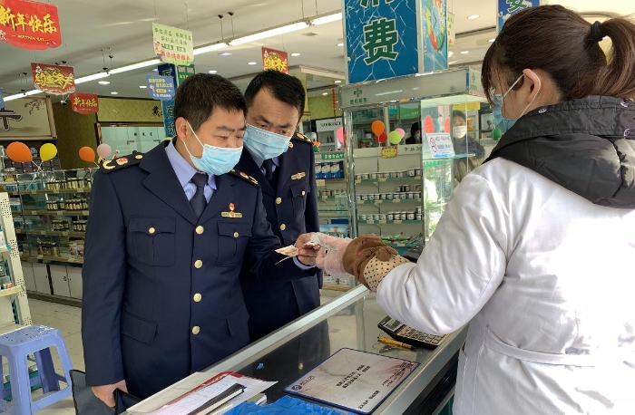 執(zhí)法人員在一家藥店檢查口罩質量和進銷價單據