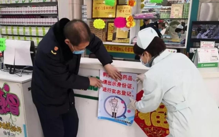 赤峰市紅山區(qū)市場監(jiān)管局監(jiān)管人員正在藥店張貼“實名登記購買退燒藥”宣傳海報。（赤峰市市場監(jiān)管局供圖）