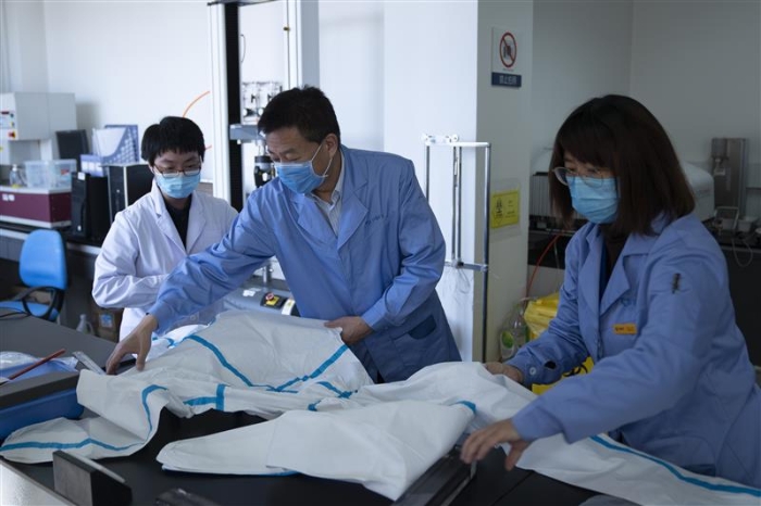 圖為趙玉杰（中）檢查醫(yī)用防護(hù)服應(yīng)急檢測(cè)工作。
