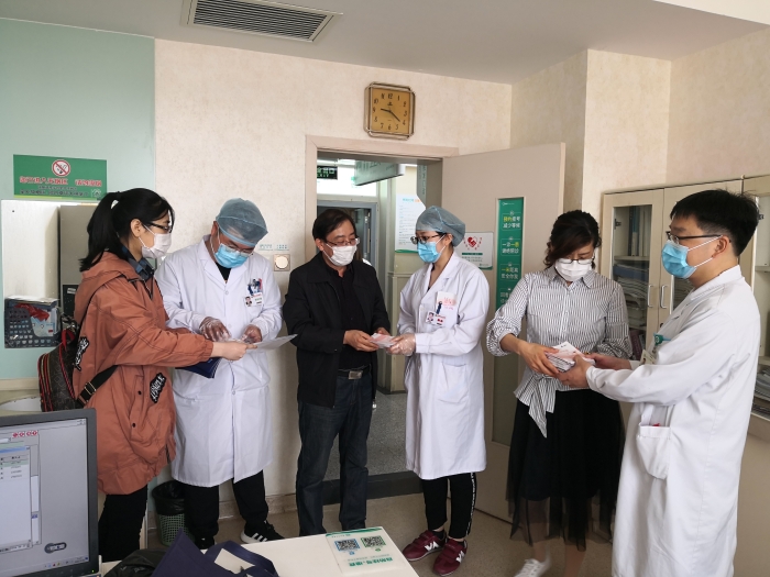 工作人員向醫(yī)護人員贈送化妝品安全科普宣傳手冊