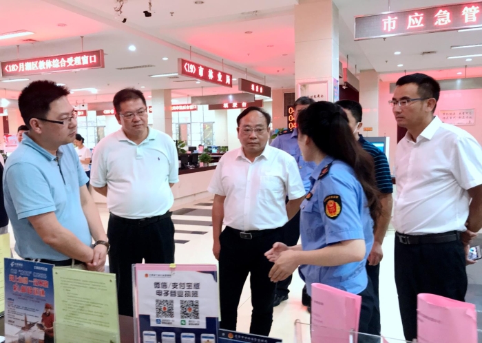 上官新晨（左三）在鷹潭市行政服務(wù)中心詳細(xì)了解“一照含證”改革情況。