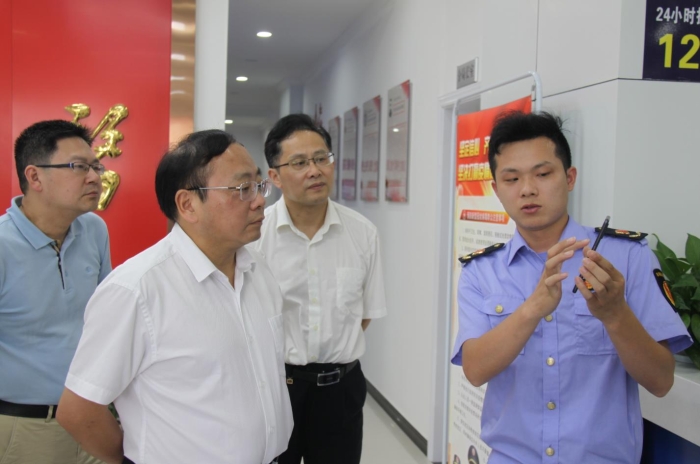 上官新晨（左二）在鷹潭市局東湖分局觀看基層執(zhí)法人員演示如何運(yùn)用智慧市場(chǎng)監(jiān)管網(wǎng)格化管理平臺(tái)開展監(jiān)督檢查工作等情況。
