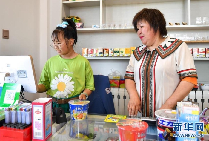 　索云（右）在位于敖魯古雅鄂溫克族鄉(xiāng)的自家超市內(nèi)，指導女兒為顧客結(jié)賬（7月14日攝）。 新華社記者 貝赫 攝