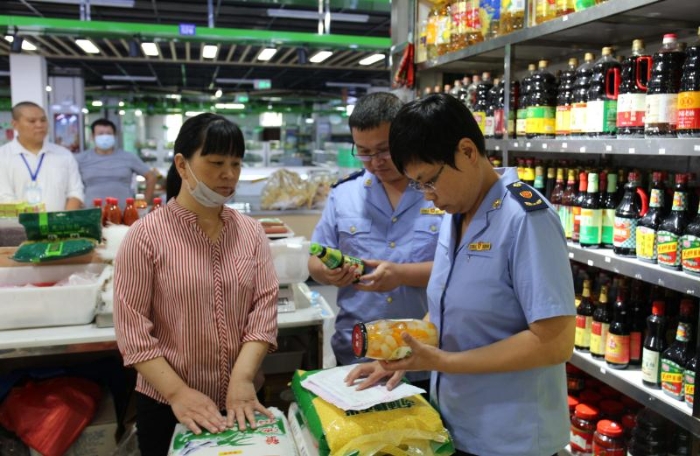 圖為執(zhí)法人員檢查農(nóng)貿(mào)市場(chǎng)內(nèi)商超在售食品。