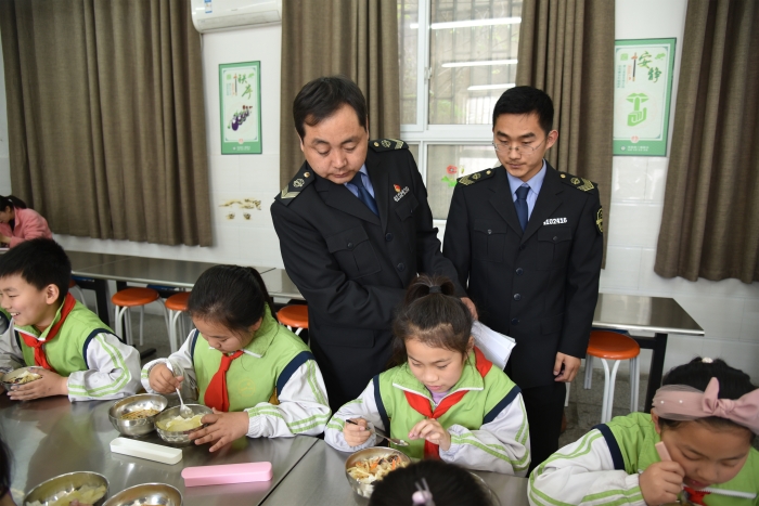 圖為執(zhí)法人員檢查食堂食品安全情況。