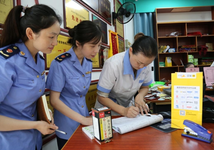 圖為執(zhí)法人員查看網(wǎng)絡(luò)藥品銷售登記，核對處方藥處方單。