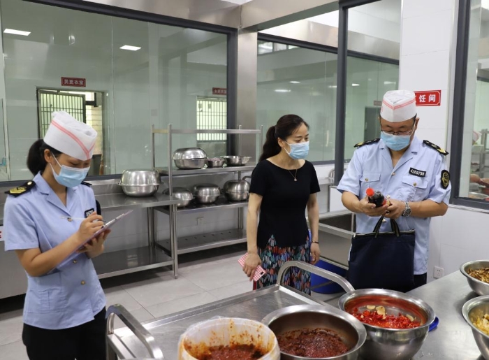 圖為執(zhí)法人員在檢查學(xué)校食堂加工制作情況。