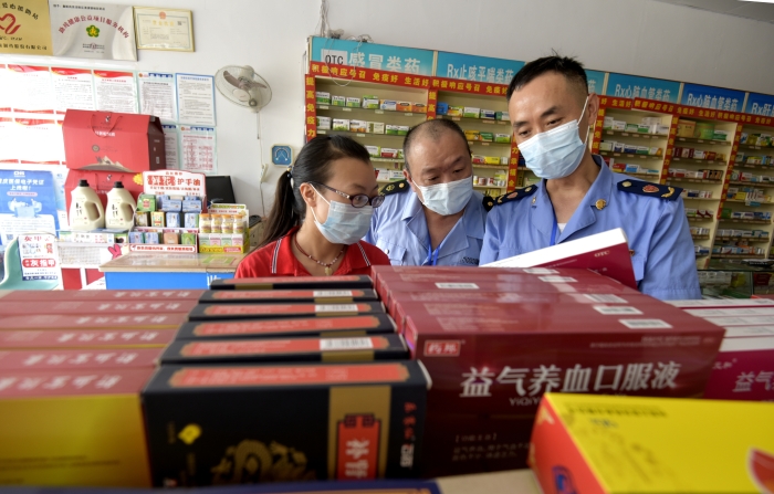 圖為執(zhí)法人員在一家藥店檢查中成藥質(zhì)量。