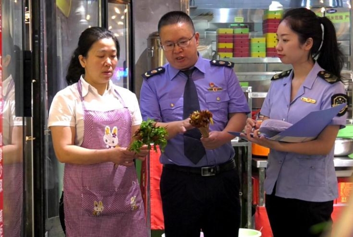 圖為執(zhí)法人員在一火鍋店檢查火鍋食品原輔材料進貨情況。