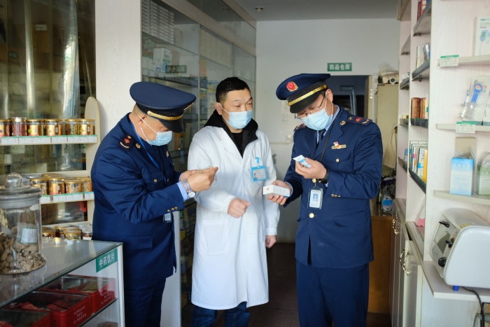 圖為執(zhí)法人員在一家藥店檢查其經(jīng)銷的藥品外包裝上標(biāo)簽是否規(guī)范，并核對(duì)相關(guān)購(gòu)銷登記臺(tái)賬的信息是否合規(guī)。