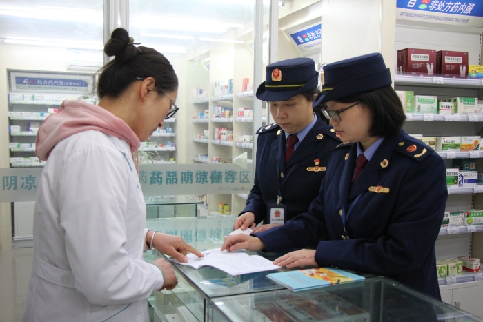 圖為執(zhí)法人員在佰藥之家大藥房發(fā)放安全用藥科普手冊。