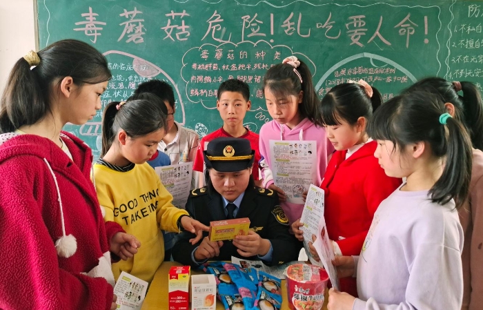 圖為該縣市場(chǎng)監(jiān)管局嶺背分局工作人員在嶺背大窩小學(xué)向?qū)W生講解如何鑒別假冒偽劣食品藥品。王雨林 段丁長(zhǎng) 攝
