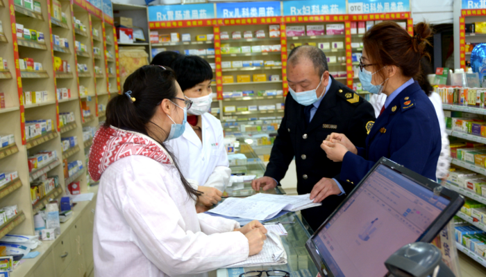 圖為執(zhí)法人員在一家藥店檢查防疫物資銷售記錄。