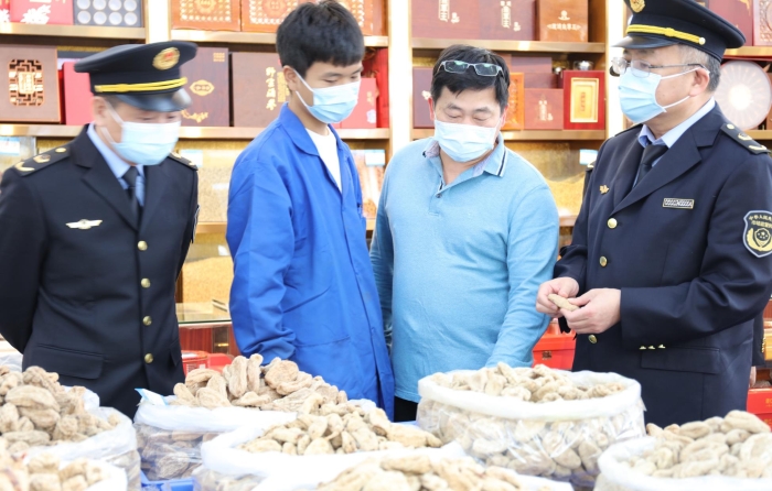 秦繼紅（右一）在中藥材市場門店查看。（喻燦華 攝）