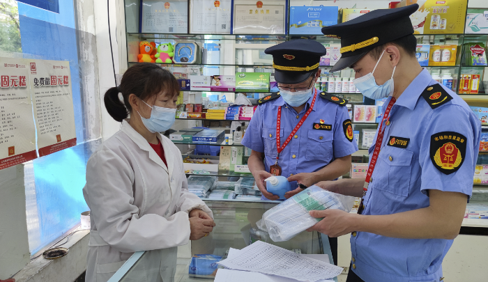 圖為執(zhí)法人員在藥店檢查防疫藥品價(jià)格。