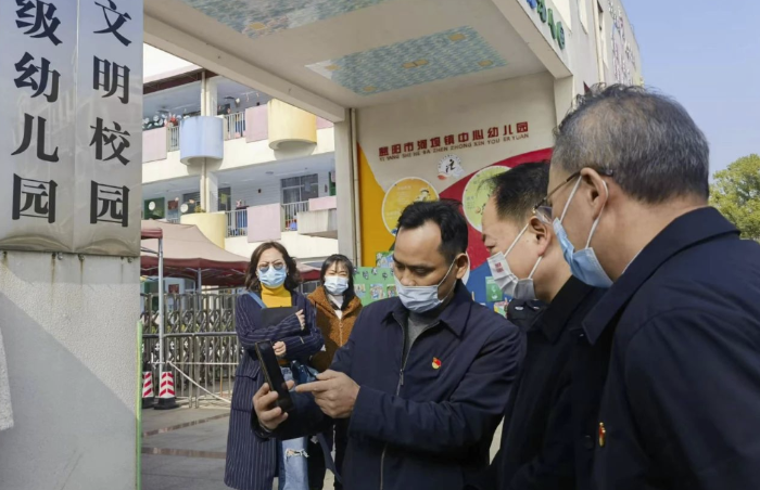 圖為樂運成（右二）通過手機客戶端查看大通湖區(qū)第一實驗幼兒園廚房實時視頻。
