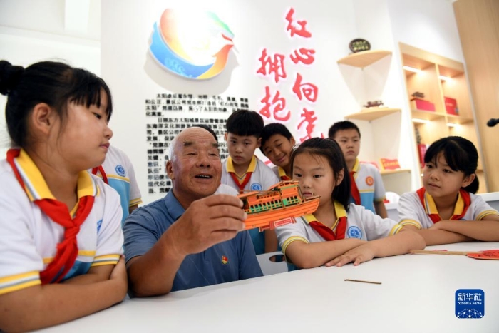 2022年8月4日，在山東省日照市東港區(qū)濤雒鎮(zhèn)東南營(yíng)村新時(shí)代文明實(shí)踐站，老黨員秦玉山給學(xué)生講“紅船故事”。新華社記者 范長(zhǎng)國(guó) 攝
