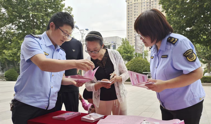 圖為該局工作人員向群眾發(fā)放化妝品科普宣傳資料。