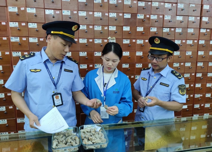 圖為執(zhí)法人員在一零售藥店檢查中藥飲片質(zhì)量情況。