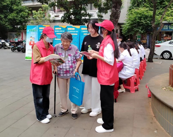 圖為工作人員向過往居民發(fā)放“全民監(jiān)測”科普宣傳資料。