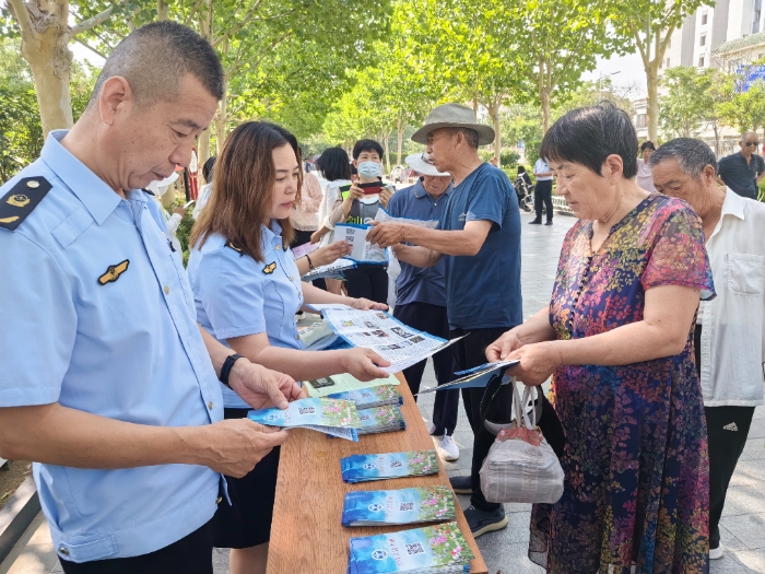 圖為工作人員向群眾發(fā)放禁毒宣傳手冊(cè)。